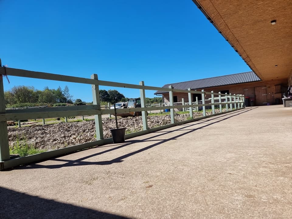 The stable block and concrete yard at Tanahken, with pale green post-and-rail fencing